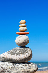 Stones balance on a background of blue sky and sea