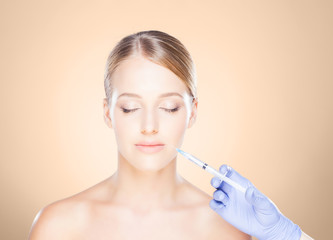 Doctor injecting in a beautiful face of a young woman. Plastic surgery concept.