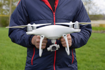 A man with a quadrocopter in his hands. A white drone is being prepared for the flight. Phantom.