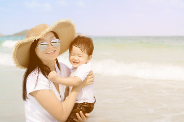Happy family - mother and small baby son sit on beach