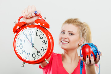 Happy woman holding clock, apple and measuring tape