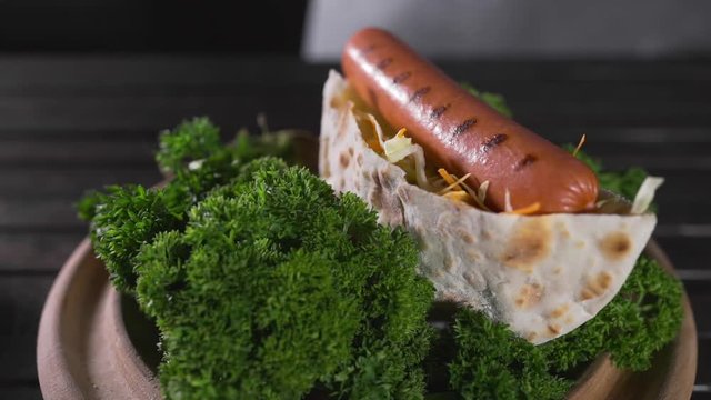 The cook makes tortilla with fresh greens, vegetables and grilled sausage, fast food, food cooking, tasty recipes, chef at the kitchen