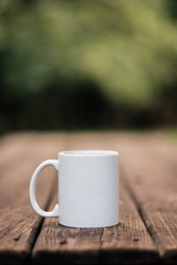 White coffee mug against green foliage