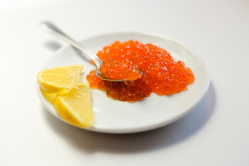 Closeup on red caviar delicacy on white plate, closeup light macro background
