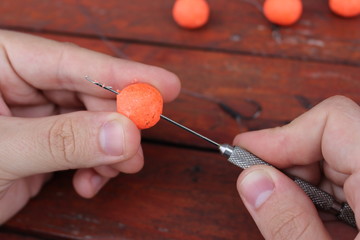 man prepare fishing protein balls on hook by drill tool. Bait, lure for carp - river fish zoom
