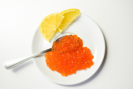 Closeup on red caviar delicacy on white plate, closeup light macro background