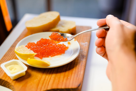 Red caviar in a white plate, closeup light background