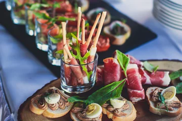 Gordijnen Gedecoreerde catering-bankettafel met verschillende hapjes-assortimenten op een feest © tsuguliev