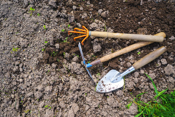 Scapula and rake on the background of fertile soil. Place for the text. The concept of agriculture. Metal garden tools