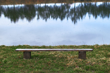 Lonely empty wooden bench by the lake