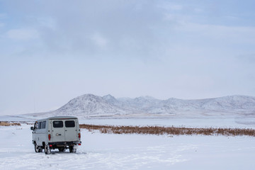 UAZ - Russian Van in prairie with snow-capped mountains on background at Mongolia