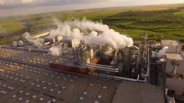 a huge concrete plant with pipes among the fields. aerial view
