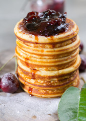 Homemade American pancakes served with cherry jam and fresh cherry on a wooden background