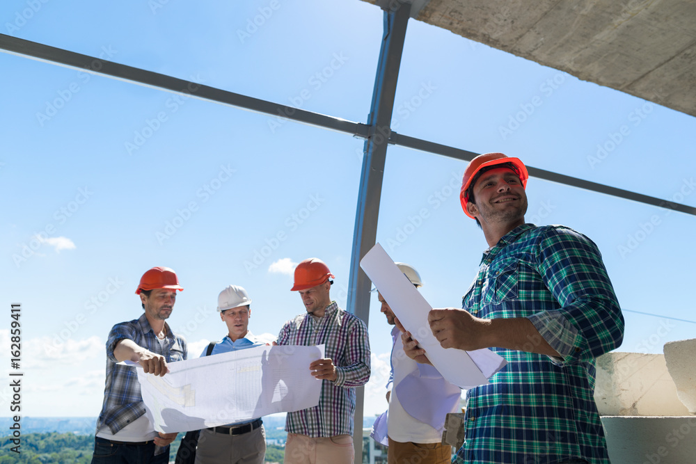 Poster group of builders in hardhat hold plan discussing project on constuction site working together build
