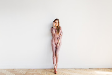 Thin elegance blond woman standing by white wall at full length