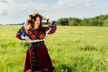 Brunette girl in embroidered shirt and burgundy skirt staying in