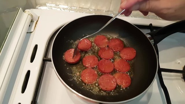 Turkish sausage - sucuk - cooking with butter on a pan over cooker. 
