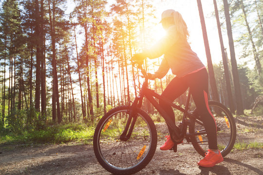 Woman riding a mountain bicycle along path at the forest