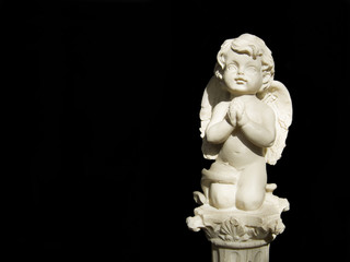 The white statuette of an angel on black background