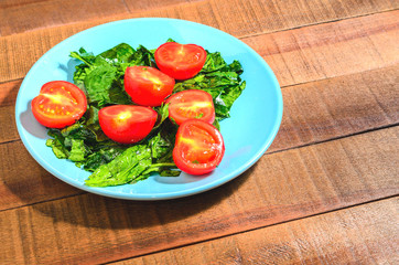 Tomatoes and greens spinach on a blue plate