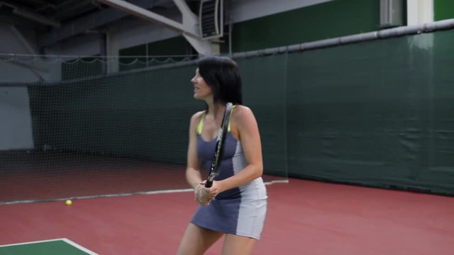 Beautiful adult woman tennis player. She playing tennis and hitting the ball