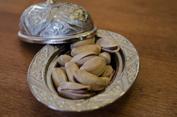 Copper bowl on a wooden table with pistachio