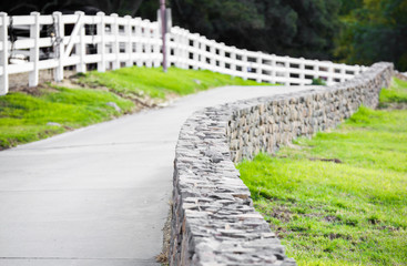 country road between a picket fence and a stone wall