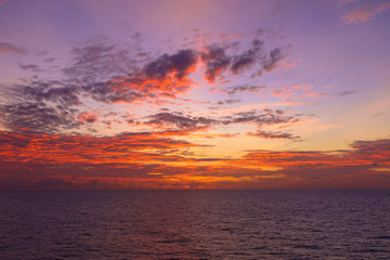 Fototapeta na wymiar Fiery orange sunset sky warm light with clouds and sea, Beautiful for background
