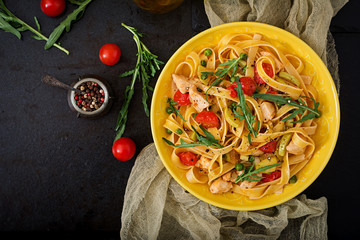 Pasta Fettuccine with tomato, zucchini and chicken fillet in bowl. Flat lay. Top view
