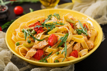 Pasta Fettuccine with tomato, zucchini and chicken fillet in bowl.