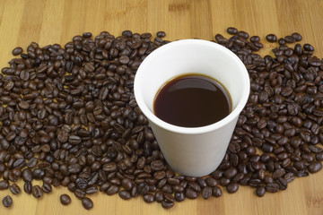 Coffe cup and coffee beeans on table.