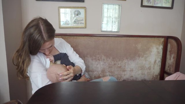 A woman breastfeeding her child in a cafe. Medium shot