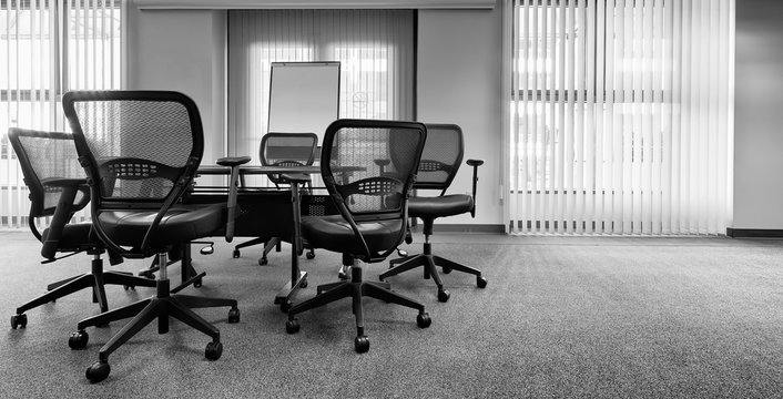 Ergonomic Office Chairs Around A Small Conference Table. Black And White With Copy Space. Banner Format