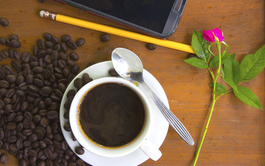Coffee cup and coffee beans on wooden background.