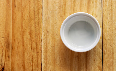 Fototapeta na wymiar white ceramic bowl on wooden table, top view