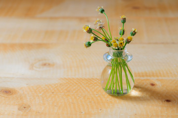 Flowers are in a vase on a wooden table.