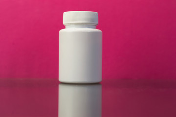 Fototapeta na wymiar Bottle for pills on a dark glass table. Beautiful pink background.