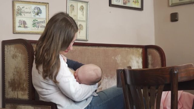 A woman breastfeeding her child in a cafe. Medium shot