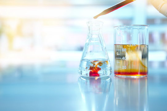flask and beaker in science laboratory with orange drop solution