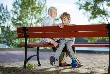 Senior woman and great grandson sitting on bench in park