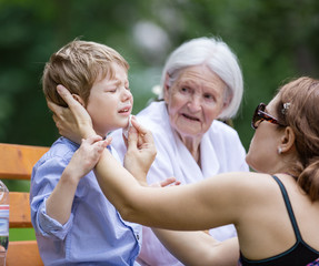 Fototapeta premium Mother treating scrape on son's chin