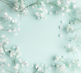 Obraz na płótnie Canvas Floral composition with light, airy masses of small white flowers on turquoise blue background, top view, frame. Gypsophila Baby's-breath flowers