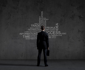 Businessman with briefcase standing over wall with text. Business, success, improvement, concept.