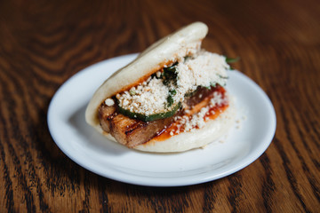 Asian gua bao with grilled brisket, teriyaki sauce, vegetables and nuts. Selective focus, small depth of field.
