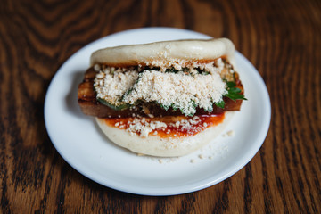 Asian gua bao with grilled brisket, teriyaki sauce, vegetables and nuts. Selective focus, small depth of field.