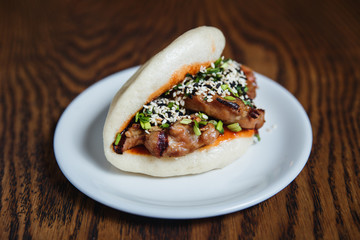 Asian gua bao with grilled chicken, teriyaki sauce, green onion and sesame seeds. Selective focus, small depth of field.