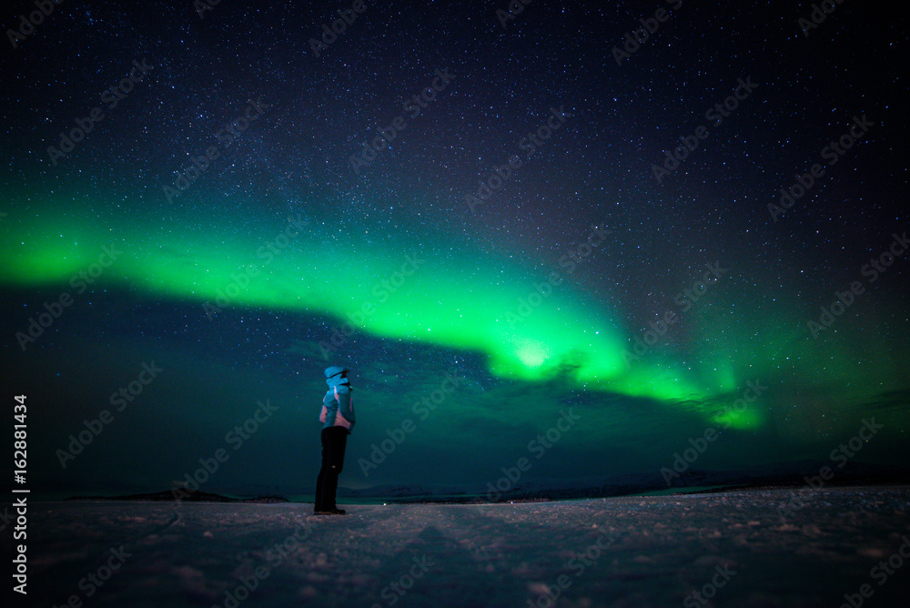 Wall mural girl watching the northern lights. abisko sweden