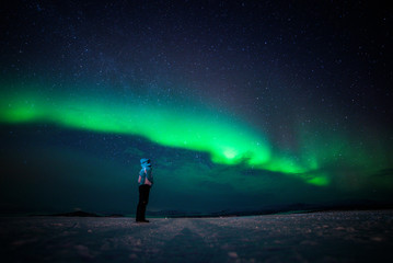 Fototapeta na wymiar Girl watching the Northern Lights. Abisko Sweden