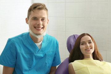 Happy young woman and male dentist after treatment in clinic