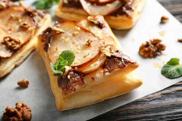 Delicious pastry with chocolate, pear and nuts on wooden table